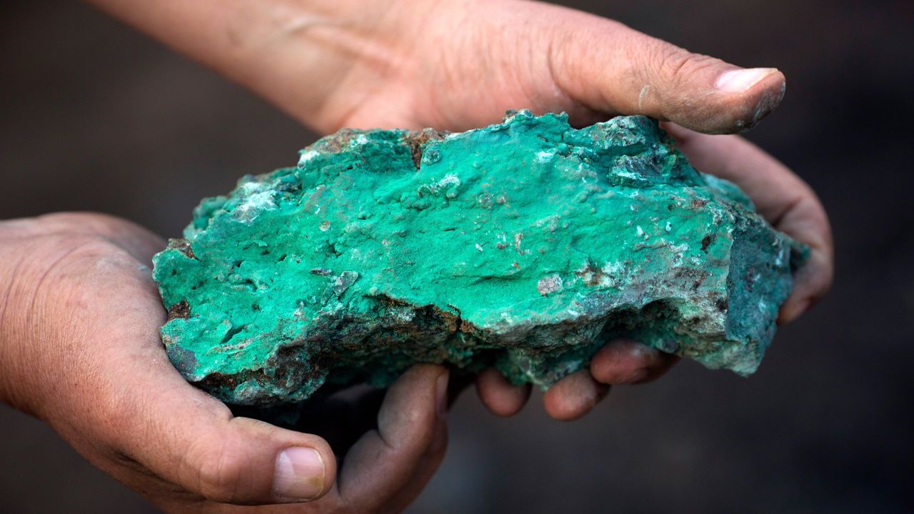 Hands holding a green copper rich ore in the Democratic Republic of the Congo.