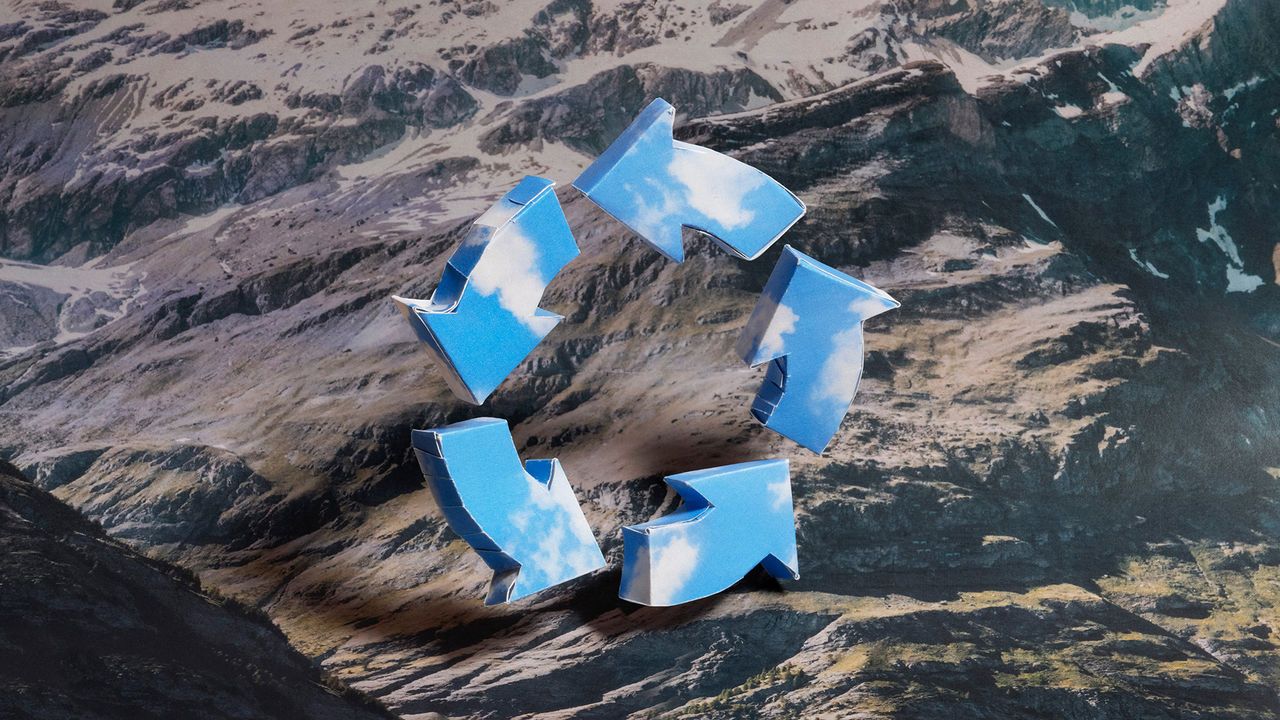 An image showing a circle of three-dimensional arrows covered in blue cloudy sky against a mountainous background.