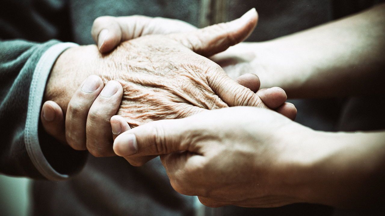 Elderly hand and caregiver.