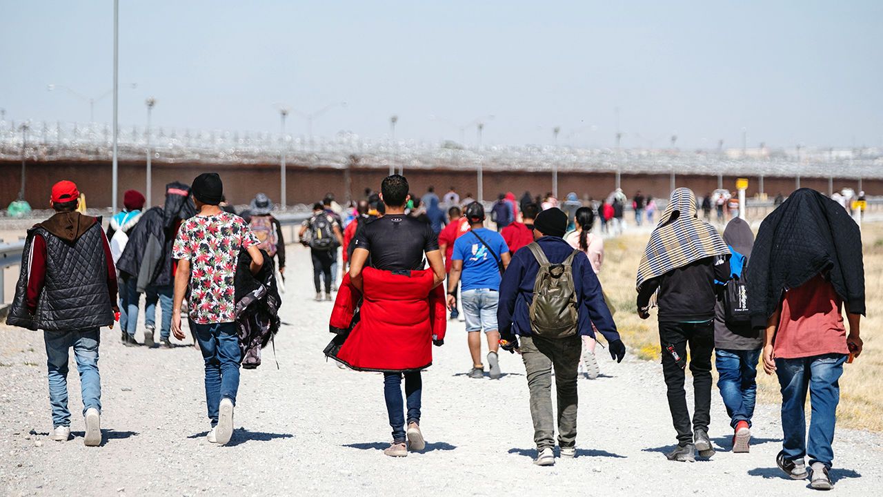 Migrants walk towards an open gate on the Mexican side of the US-Mexico border in Ciudad Juarez, Chihuahua state, Mexico